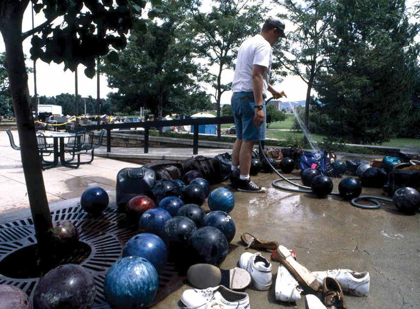 On campus, man cleaning off bowling balls from LSC after the Spring Creek Flood.