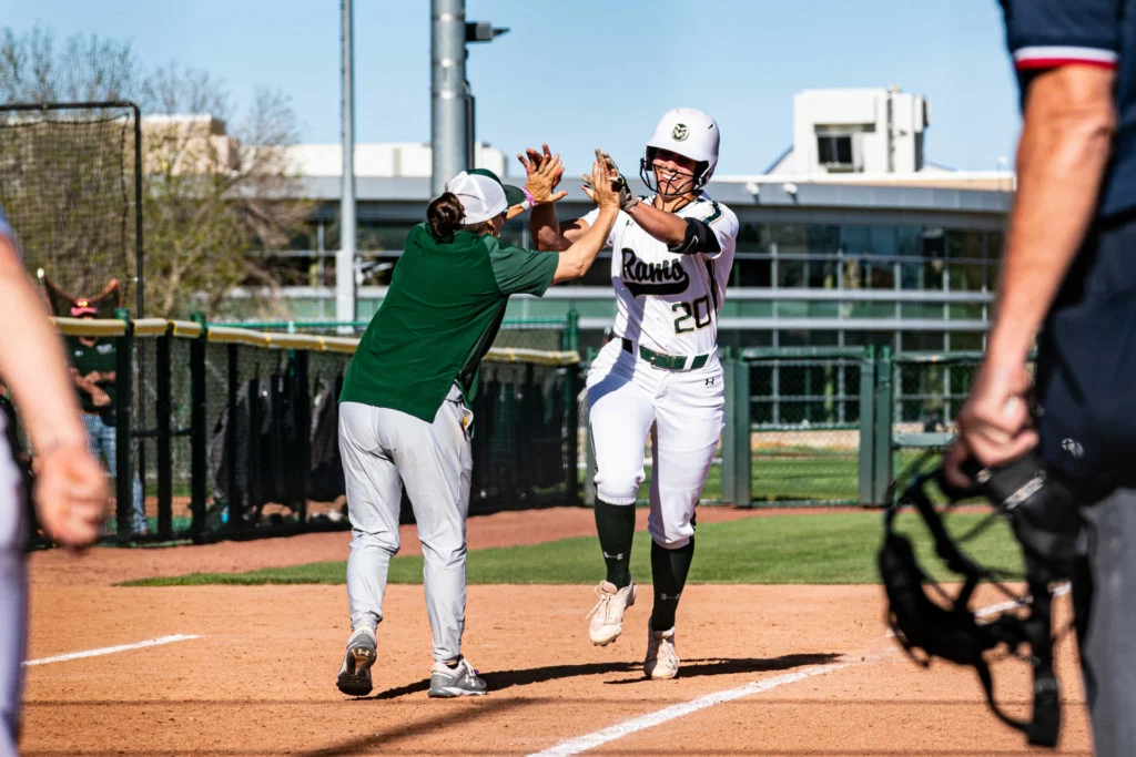Two softball players celebrate at home plate.