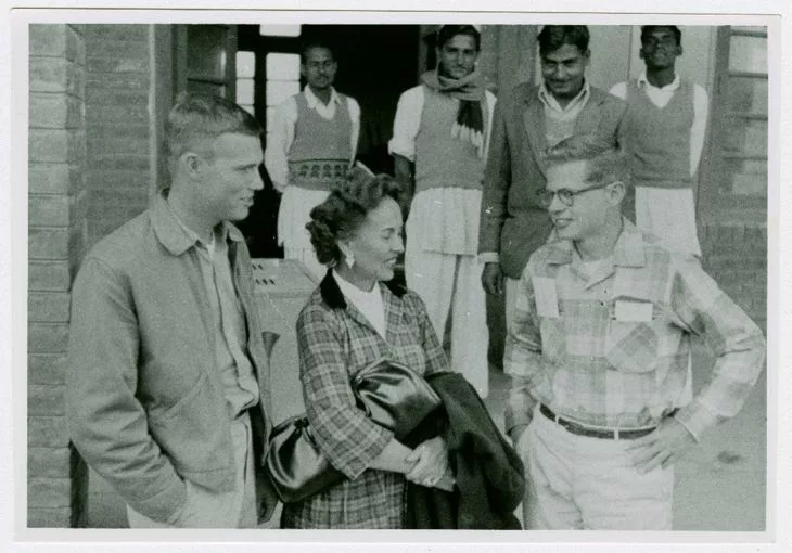 Black and white photo of Pauline Birky with two Peace Corps volunteers and four Pakistani men in the background